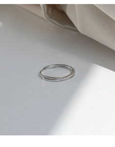 Detailed close-up of a silver crisscross open ring with shimmering micro-pave zircon stones