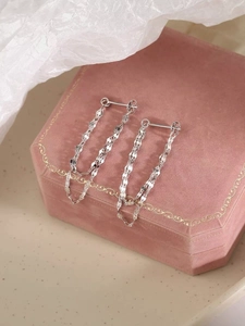 Détail de boucles d'oreilles pampilles en argent S925 sur une boîte à bijoux en velours