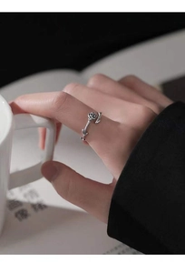 Detailed view of an S925 silver thorn rose ring worn by a model in a cozy setting