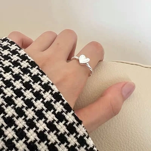 Macro detail of silver twisted heart ring showing textured band on a model's finger