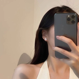 S925 silver heart stud earrings with textured finish shown on ear in a mirror selfie