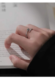 Detailed view of vintage S925 silver thorn rose ring worn while holding a book