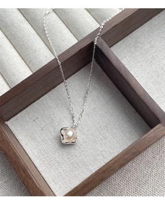 Detailed close-up of a square irregular silver pendant with a white freshwater pearl inside