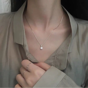 Close-up of minimalist S925 silver necklace with single sparkling diamond on model