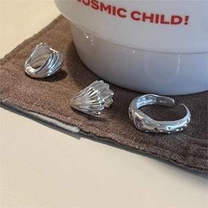 Macro detail of S925 silver rings with pink heart gem and shell texture on linen cloth