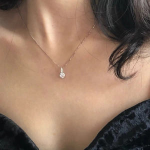 Close-up of minimalist S925 silver single diamond necklace on a rose gold box chain