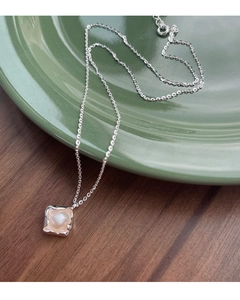 Macro detail of S925 silver necklace with irregular pearl pendant on vintage tray