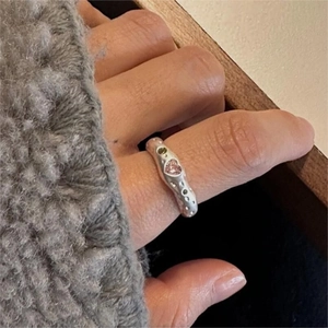 Macro detail of irregular S925 silver ring with pink heart stone and green side diamonds