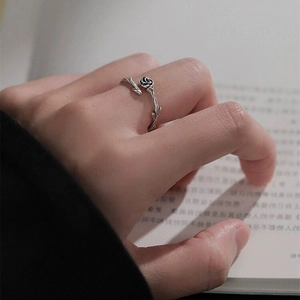 Vintage S925 sterling silver rose thorn open ring shown on hand over book background