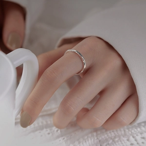 Minimalist S925 sterling silver Mobius ring with Luck engraving on a hand with coffee cup