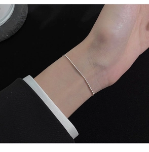 Detailed close-up of a delicate S925 sterling silver snake bone chain bracelet on a wrist