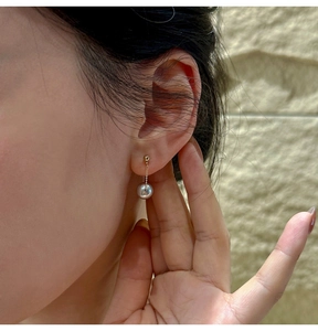 Close-up of S925 silver earring featuring a dark grey round pearl on a golden chain
