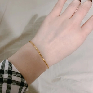 Detail of minimalist gold snake bone chain bracelet worn on wrist for a layering look