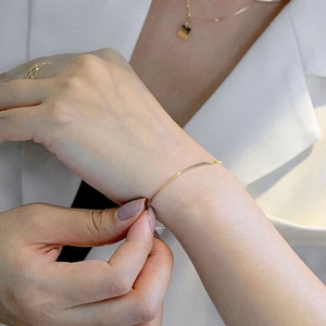 Minimalist slim gold snake chain bracelet on model wrist with elegant polished finish