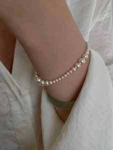 Elegant gradient pearl bracelet on female wrist with silk background and jade bangle