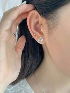 Close-up of S925 silver oval marble stud earrings and minimalist rings on model