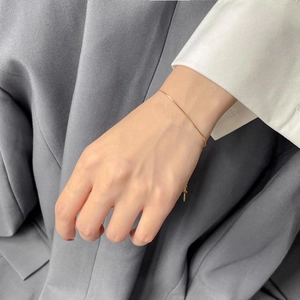 Detail of a minimalist gold snake chain bracelet worn on a wrist with business attire