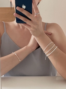 Macro view of a layered S925 silver bracelet set and a chain-link ring for women
