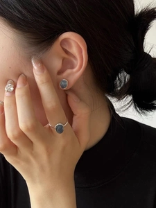 Detail view of oval aquamarine silver studs and matching ring set on a model