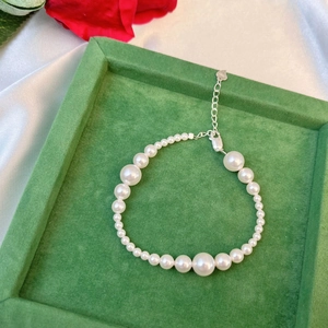 Detail of S925 sterling silver pearl bracelet with heart charm on green velvet tray