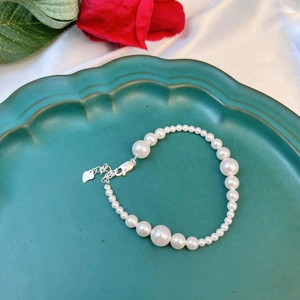 Macro shot of S925 silver pearl bracelet featuring gradient beads and heart charm