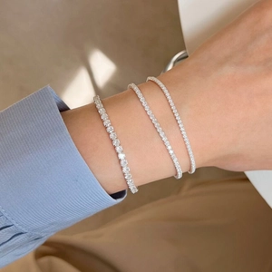 Detailed view of three-piece silver pavé tennis bracelets stacked on a wrist