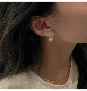 Detail of S925 silver pearl drop earrings with elegant gold chain on model