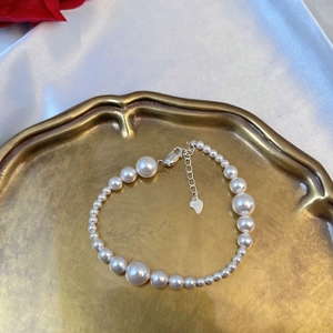 Detail of S925 sterling silver pearl bracelet with heart charm and lobster clasp