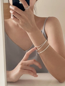 Detail of layered S925 silver bracelet with pearls and hollow chain ring on model hand