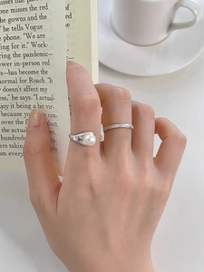 Close-up of S925 silver rings set with freshwater pearl worn on hand in cafe setting