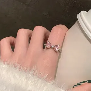 Close-up of S925 silver ring featuring pink zircon bow worn on finger in cozy setting