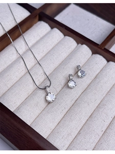 Macro view of a sparkling round-cut diamond pendant and earring set in a wooden jewelry box