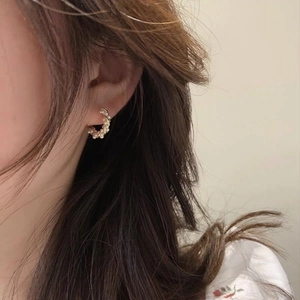 Detail shot of a gold-wrapped hoop earring with white pearls on a model ear