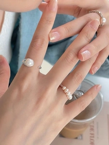 Detailed close-up of S925 sterling silver and gold freshwater pearl rings on hand