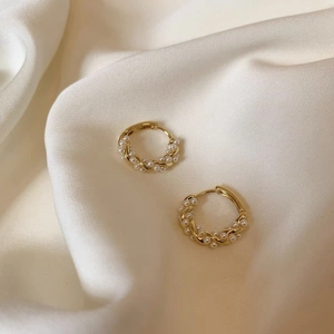 Elegant S925 silver gold-plated spiral pearl earrings on white silk fabric background
