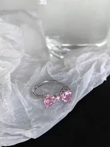 Detail of silver bow ring featuring pink heart-shaped zircons on white pleated paper