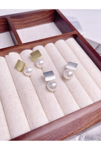 Détail de boucles d'oreilles carrées en argent S925 avec perles blanches et finition or
