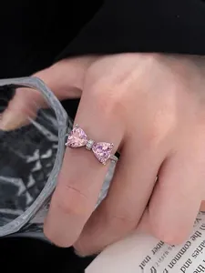 Detailed shot of S925 silver ring featuring pink heart zircon bow on woman's finger