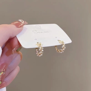 Detail of twisted gold earrings with small white pearls on a display card holder