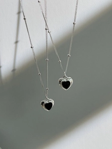Close-up of S925 silver heart necklaces with black onyx pendants in a layered view