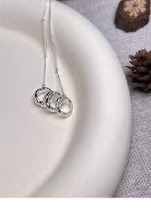 Detailed view of S925 sterling silver triple interlocking ring necklace on ceramic plate