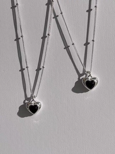 Detailed view of S925 sterling silver heart necklaces with black onyx on light background