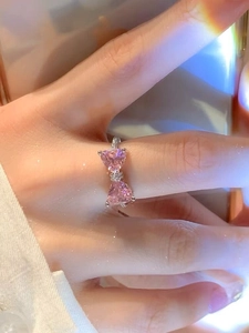 Detail of S925 silver ring featuring pink heart-shaped stones in a bowknot design on hand