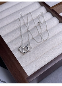 Detailed macro view of triple-interlocked silver rings with hammered texture on beige velvet