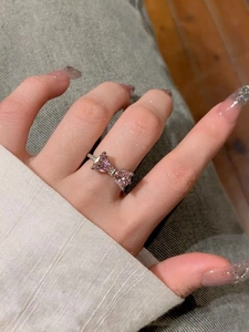 Detailed macro of a silver bow ring with pink triangular stones and micro-pave setting
