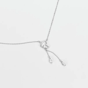 Détail du collier argenté avec pendentif papillon, pompons et pierres goutte