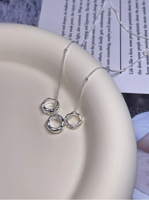 Detail of interlocking triple rings necklace with wavy texture on ceramic dish