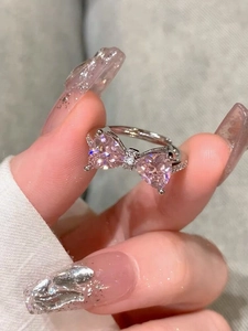 Macro detail of silver bow ring featuring pink heart stones and a sparkling pavé band