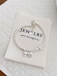 Detail of silver bow pendant and pearl on irregular S925 sterling silver bead bracelet