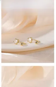Macro detail of C-shaped gold-plated silver earrings with square-cut zircon stones